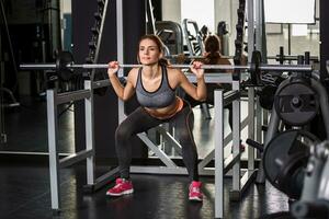 muscolare giovane donna fare esercizi su il simulatore nel il Palestra foto