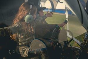 preteen ragazza con braccia disteso per lato seduta nel elicottero cabina di pilotaggio foto