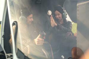 sorridente adolescenziale ragazze nel pilota auricolari dando alto cinque nel elicottero foto