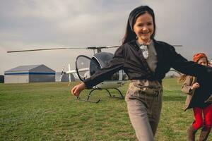 allegro gemello ragazza in esecuzione su sfondo di elicottero su campo di aviazione foto