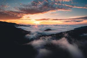 il sole sorge nella nebbia e nelle montagne al mattino foto