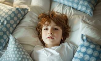 ai generato un' poco ragazzo posa nel letto con blu e bianca cuscini in giro il suo testa foto