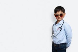 Sorridente ragazzino con stetoscopio e occhiali sfondo isolato con copia space