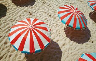 ai generato rosso bianca e blu a strisce ombrelli su un' sabbioso spiaggia foto
