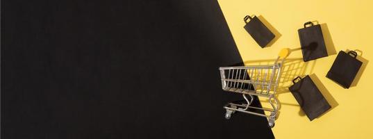 Piatto in miniatura laici carrello del supermercato con le borse della spesa in vendita venerdì nero su sfondo giallo foto