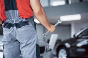 mani del meccanico di automobili con una chiave inglese in garage foto