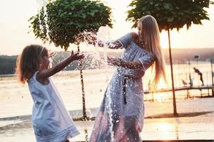 una donna che gioca con un bambino vicino all'oceano nel parco al tramonto foto