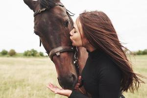 una ragazza felice comunica con il suo cavallo preferito. la ragazza ama gli animali e l'equitazione foto