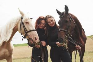 due giovani belle ragazze in marcia per cavalcare vicino ai loro cavalli. amano gli animali