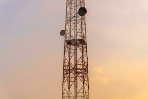 telecomunicazione Torre antenna e satellitare piatto con sera cielo sfondo. foto