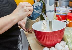 casalinga sbattere pancake pastella nel cucina con miscelatore e ciotola foto