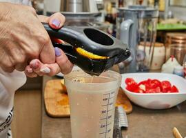 professionale capocuoco spremitura fresco Limone succo in misurazione tazza nel moderno cucina foto