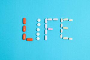 vita parola a partire dal colorato medicina pillole isolato su blu sfondo, supplemento, vitamina, colorato foto