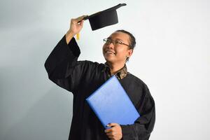 espressive di adulto Indonesia maschio indossare la laurea veste, cappello e occhiali, asiatico maschio la laurea portare vuoto blu certificato isolato su bianca sfondo, espressioni di ritratto la laurea foto