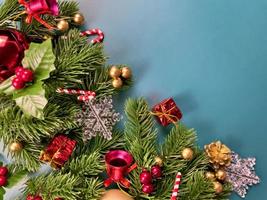 decorazioni natalizie, foglie di pino, palline dorate, fiocchi di neve, bacche rosse e bacche dorate su sfondo blu foto