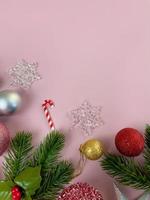 decorazioni natalizie, foglie di pino, palline dorate, fiocchi di neve, palline rosse su sfondo rosa foto