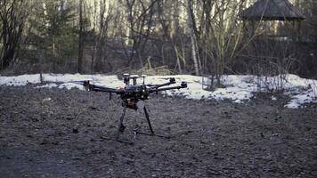 vicino su per nero fuco in piedi su il terra prima il volo, aereo video e foto tiro concetto. clip. quadcopter di partenza per ruotare suo lame e assunzione spento.