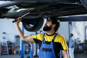 meccanico usi lampada leggero per asini situazione prima mutevole vecchio auto freno fluido con nuovo uno nel riparazione negozio. dipendente nel box auto fare verifica su veicolo sospeso su sollevamento foto