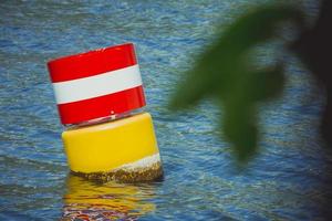 boa galleggiante di navigazione in acciaio giallo rosso e bianco nell'acqua di mare blu foto