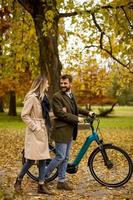 giovane coppia nel parco autunnale con bicicletta elettrica foto