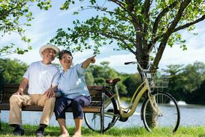 contento e salutare coppia asiatico seduta sedia accanto un' bicicletta famiglia e amicizia stile di vita, godimento di attivo gli anziani, e all'aperto attività dopo la pensione, Salute cura assicurazione concetto foto