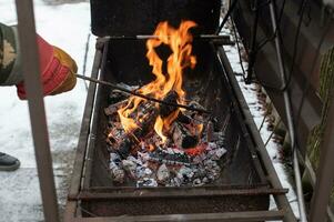 accendendo un' fuoco nel il barbecue, svolta al di sopra di ardente carboni foto
