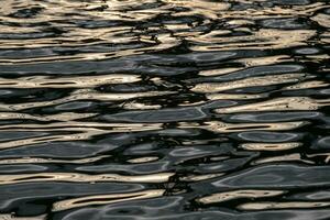 acqua superficie ondulazione con riflessione e d'oro splendente foto