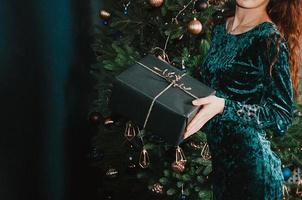 donna con una confezione regalo vicino all'albero di natale foto