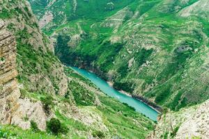 montagna paesaggio con un' in profondità canyon con un' blu fiume lungo quale un' il motore barca si sposta foto