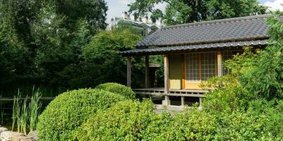 tè Casa dietro a stagno nel giapponese giardino foto