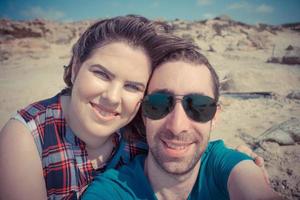 giovane coppia che si fa selfie con lo smartphone o la fotocamera in spiaggia foto