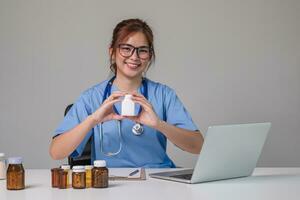 giovane asiatico medico nel un' bianca medico uniforme con un' stetoscopio utilizzando un' laboratorio computer e tavoletta per organizzare e classificare medicinali nel preparazione per amministrazione per pazienti. foto