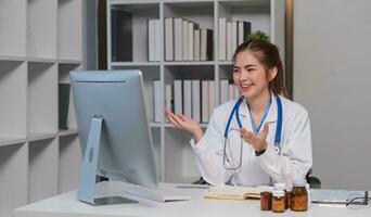 bellissimo asiatico medico sorridente utilizzando il computer portatile computer spiegando dettagliato medico informazione in linea a ospedale Salute medico concetto. foto