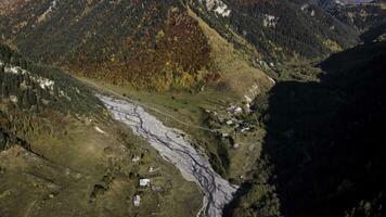 aereo Visualizza di un' affascinante piccolo villaggio collocato giù nel il valle vicino foreste colline. filmato. volante al di sopra di il montagne coperto di colorato autunno alberi. foto