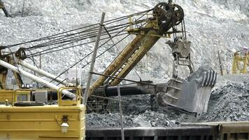 scavatrice e ferrovia con minerale. scavatrice riempimenti con minerale rotaia macchine nel sfondo di Aperto fossa. pesante trasporto nel estrazione industria foto