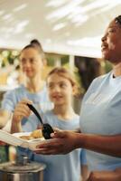 vicino su Visualizza di donne il volontariato a cibo guidare di servendo caldo pasti con gentilezza per il senza casa le persone. dettagliato tiro di femmina beneficenza lavoratori preparazione cibo donazioni per il Di meno fortunato. foto