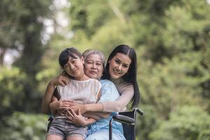 nonna felice in sedia a rotelle con sua figlia e suo nipote in un parco, vita felice tempo felice. foto