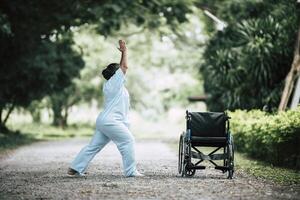 donna anziana di terapia fisica con sedia a rotelle nel parco foto