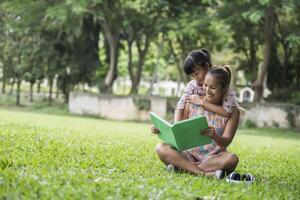 madre e figlia che leggono una favola a sua figlia nel parco foto