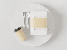 scatole per il pranzo, bicchieri, cucchiai di plastica e forchette posti su un piatto bianco. foto