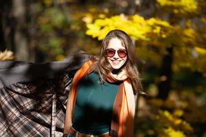 giovane donna in occhiali da sole nella foresta autunnale foto