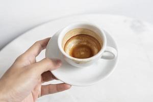 mano che tiene la tazza di caffè espresso vista dall'alto sul tavolo nella caffetteria.