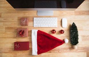 confezione regalo rossa durante le vacanze di natale in ufficio con decorazioni natalizie sul tavolo. foto