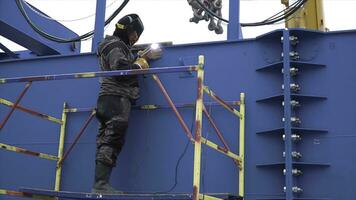 Lavorando uomo saldatura acciaio telaio luogo costruzione. clip. uomo nel il maschera fa saldatura strutture su il costruzione luogo foto