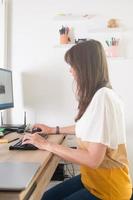 donna attraente che lavora a casa. scrivania in legno e sedia ergonomica in ginocchio foto