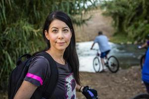 donna in bicicletta in campagna e guardando la telecamera