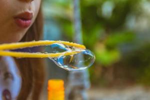 primo piano di una bambina che fa le bolle di sapone