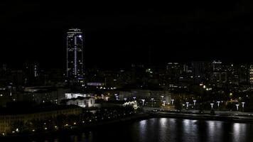 notte città vicino il fiume. azione metraggio.a metropoli con enorme uffici, luci e un' strada dove macchine muoversi. foto