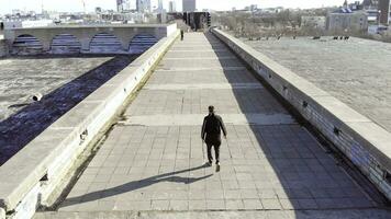 superiore Visualizza di uomo a piedi su tetto su sfondo di città. scorta. giovane uomo passeggiate ripidamente nel mezzo di strada su sfondo di città orizzonte su chiaro giorno foto