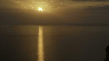 mozzafiato tramonto al di sopra di il atlantico oceano con il luminosa d'oro sole In arrivo giù per il orizzonte. sparo. aereo di il calma oceano, nero scogliera, e bronzo tramonto. foto